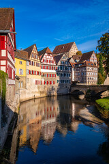 Naklejka premium Schwäbisch Hall is a picturesque small town in Baden-Württemberg (Germany). Historic old town buildings with colorful half-timbered facades and a stone bridge are reflected in River Kocher in autumn.