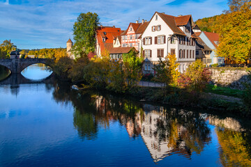 Obraz premium Schwäbisch Hall is a picturesque small town in Baden-Württemberg (Germany). Historic old town buildings with colorful half-timbered facades and a stone bridge are reflected in River Kocher in autumn.