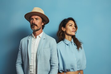 A man and a woman are standing next to each other, both wearing blue shirts