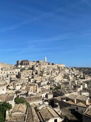 Obraz premium Stunning view of the ancient city of Matera, Italy, featuring historical stone buildings under a clear blue sky. Iconic UNESCO World Heritage Site, Sassi di Matera.