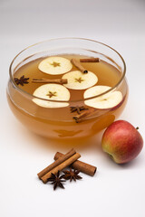 Hot apple punch with spices in a transparent container on a white background