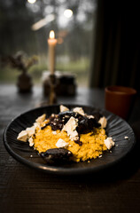 Mamaliga with cheese and smoked sausages on a black plate and a glass of kefir.Hominy dish.The concept of Moldavian cuisine