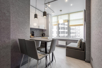 Clean kitchen in a small cozy contemporary studio apartment. Table and chairs in the foreground. Built in household appliance