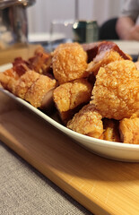 Torreznos, a typical dish of Spanish cuisine. A white bowl filled with fried pork chops on a wooden table