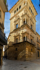 Streets of the city of Ubeda. A stone building with a large tower divides an alley into two narrower streets.
