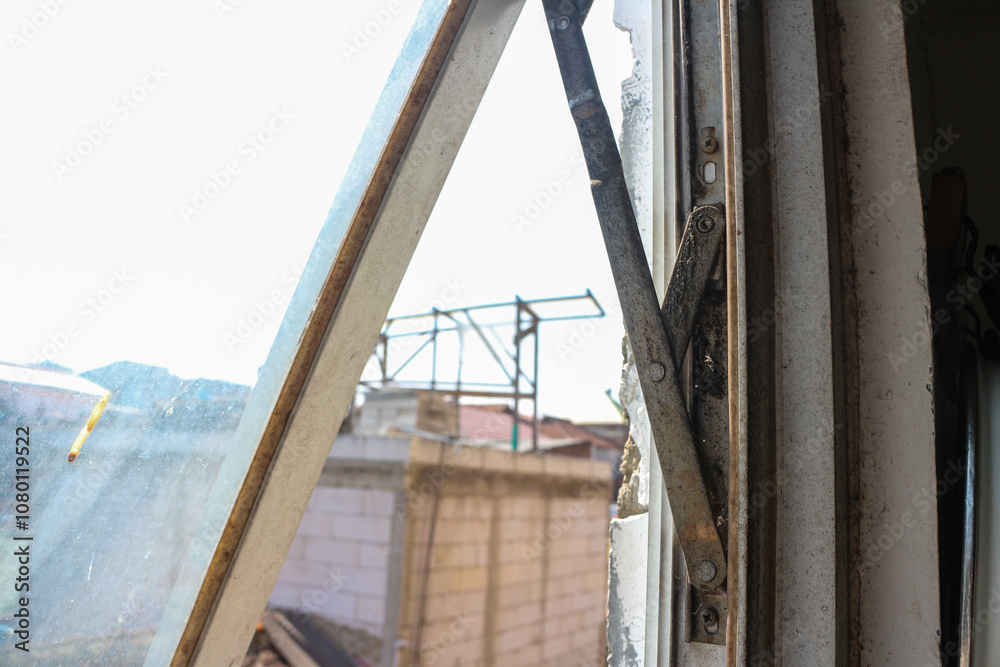 Poster a view through a slightly open window revealing a glimpse of the building outside. old rusty window 