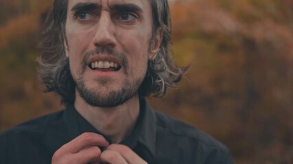 Funny lost crazy Man – Young, funny Slavic man with long hair in black shirt in autumn forest, close-up, looking around confused, adjusting shirt, leaving 