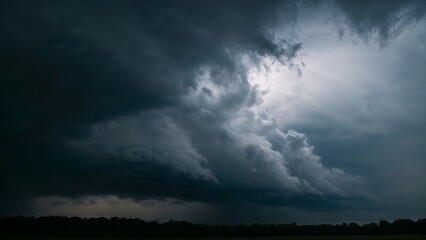 Fototapeta premium Moody dark clouds above with rays of light breaking through, indicating an approaching storm, copy space