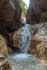 Serene Waterfall Cascading Through Rocky Canyon Surrounded by Lush Greenery, Capturing Nature's Beauty in a Tranquil Environment