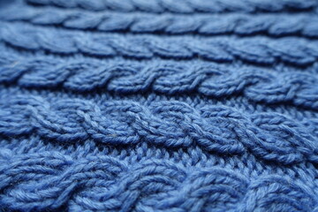Close shot of handmade blue knitted fabric with cable braids