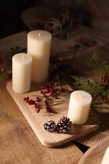 White candles with holiday greenery, creating a festive and peaceful winter ambiance