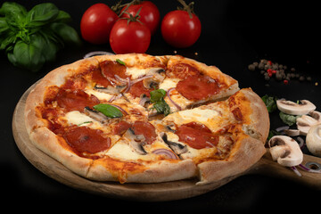 Homemade pepperoni pizza with basil on black background