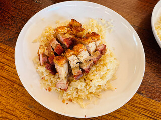 Rice cooked with chicken soup topped with Crispy pork in Phuket, Thailand.