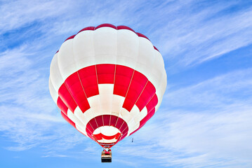 Colorful hot air balloon flying over blue sky with white clouds	