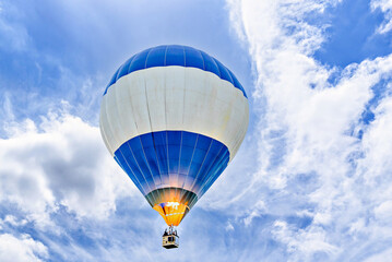 Obraz premium Colorful hot air balloon flying over blue sky with white clouds 