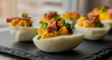  deviled eggs topped with crispy bacon and green onion, creating a savory and colorful appetizer....