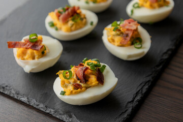  deviled eggs topped with crispy bacon and green onion, creating a savory and colorful appetizer. Perfect for party starters, gatherings, or holiday platters