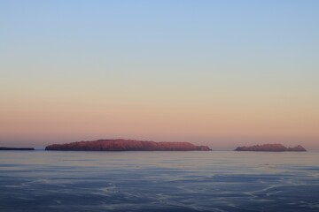 Serene view of distant islands at sunset with a calm ocean.