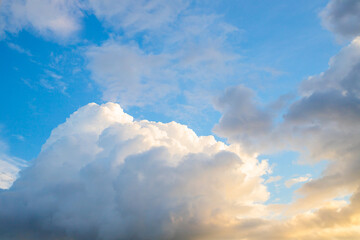 Bright sky with fluffy white clouds during sunset creating a picturesque atmosphere in a tranquil outdoor setting