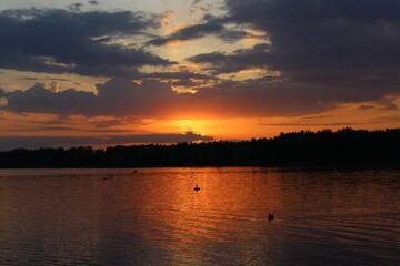 Orange sunset over the lake, beautiful abstract nature background, landscape, bright sky, spring warm evening, bright colors of spring, water, reflection, walk in the park, sun rays, fiery sunset 