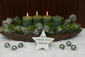 Dritter Advent: Adventskranz mit grünen Kerzen und Adventschmuck im Schnee.
