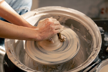 Fototapeta premium close up the clay modeling studio young girl hands giving shape to clay on a potter's wheel applied art clayware old craftsmanship