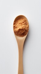 A wooden spoon filled with fine brown powder rests against a white background,