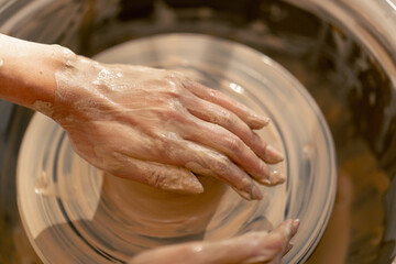 close up the clay modeling studio young girl hands giving shape to clay on a potter's wheel applied art clayware old craftsmanship teacher helps