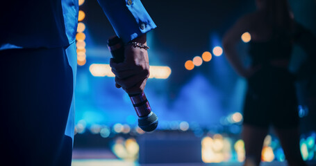 Close Up of a Hand Holding a Microphone at a Concert. Music Artist Preparing to Take the Stage,...