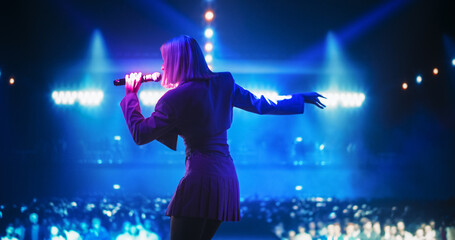 Energetic Pop Artist Performing on Stage in Pink Feminine Clothes. Excited Audience Listening to the Tunes and Being Illuminated by a Vibrant Light Show. Footage from the Back