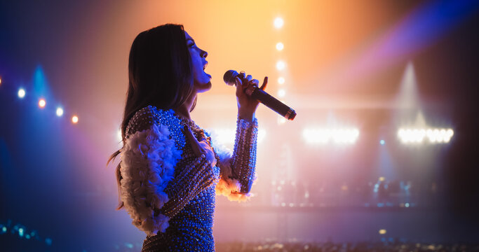 Talent Show Performance: Portrait of a Young Female Pop Singer on a Stage with Colorful Neon Lighting. Musician Singing a Powerful Solo, Poring Her Heartfelt Emotions into Beautiful Music