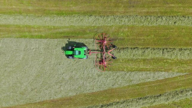 Tractor in field preparing hay bales for collection in an English agricultural rural countryside