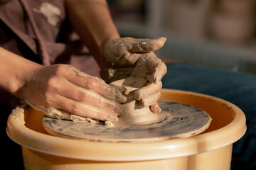 close up hands top shot in clay modeling studio young girl hands giving shape to clay on a potter's wheel applied art clayware old craftsmanship mechanical potter's wheel