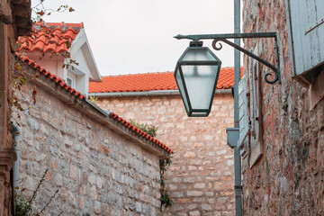 Hanging street lamp for illuminating narrow stone alley in old european town