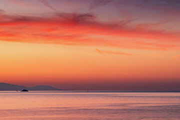 Breathtaking orange and pink hues dominate the sky during a vibrant sunset over a tranquil ocean, creating a serene and colorful seascape