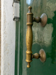 Close-up of a vintage brass door handle on a green door.