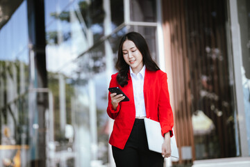 Using laptop, video call, Smiling young Asia business woman leader entrepreneur in red color suit...