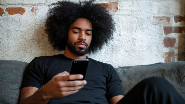 A man with a black shirt and dreadlocks is sitting on a couch