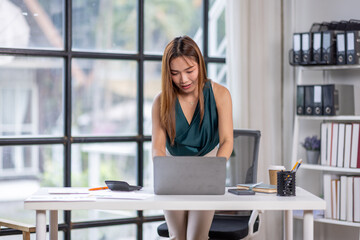 Asian Business woman using calculator and laptop for doing math finance on an office desk, tax, report, accounting, statistics, and analytical research concept	