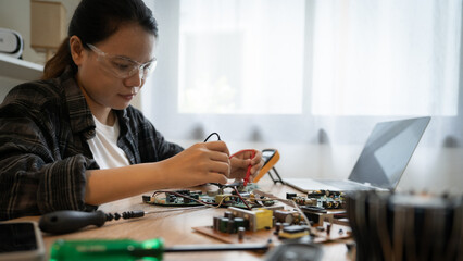 A woman is working on a computer repair. She is wearing safety goggles and is focused on her task