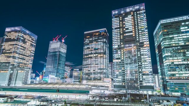 【東京都・中央区】東京・八重洲の超高層ビル群と東京駅を走る電車の光跡　タイムラプス　パンライト　
The skyscrapers of Yaesu and light trails of train running through Tokyo Station - Tokyo, Japan - Time lapse video - pan right