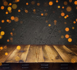 Festive, Christmas, New Year background. Evening. Night. Homely, cozy background. Abstract background. An empty wooden table. Golden lights. Garland. Defocus lights. Bokeh. Copy space