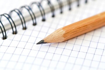A simple study or work setup with a pencil and spiral notebook on a table
