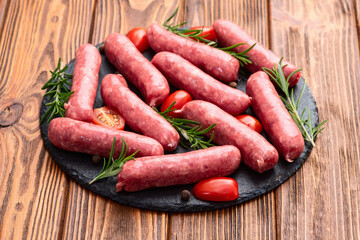Raw beef sausages with rosemary and tomatoes photography . Top view