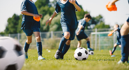 Young boys playing soccer training game. Junior football practice competition between players running in a duel and kicking a soccer ball. Training and football match between youth soccer teams