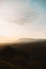  Softly lit hills and distant mountains under a golden sunset, creating a peaceful natural landscape