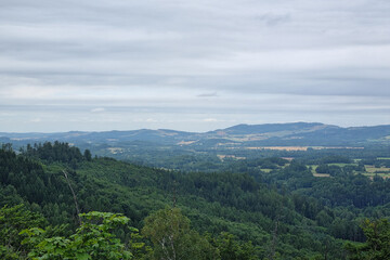 Obraz premium Scenic Overlook of Lush Green Hills and Distant Mountains Under a Cloudy Sky