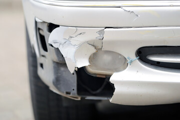 Damaged car front bumper after an accident on the road closeup. Car accident. Damaged bumper and...