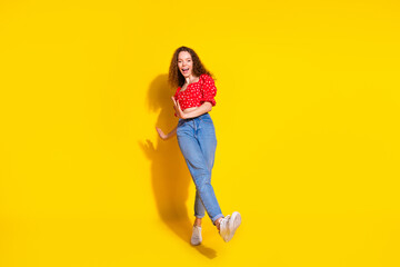 Full body photo of attractive young woman step dancing have fun dressed stylish red clothes isolated on yellow color background