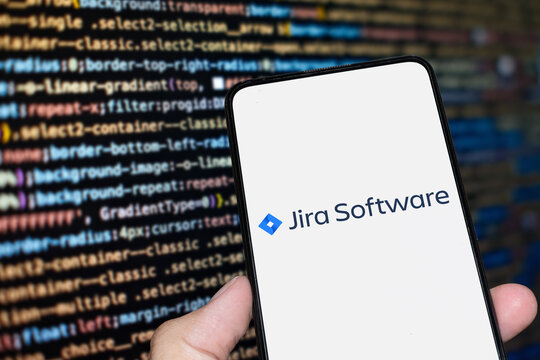 Jira Software logo sign on the smartphone screen with code background. London, UK, 11.14.2024